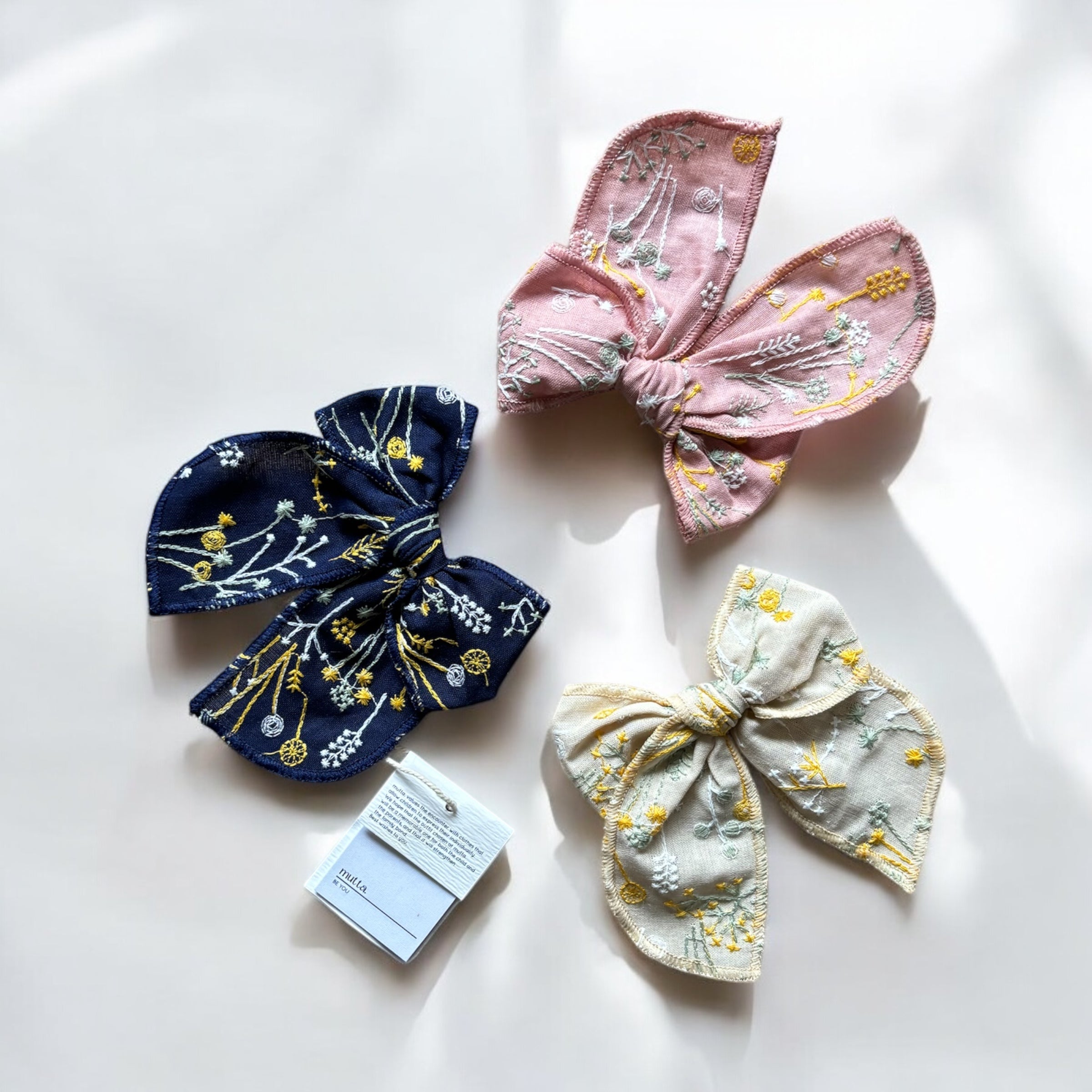 「刺繍入りのレトロシックなヘアリボン。ナチュラルカラーの生地にボタニカル柄の繊細な刺繍が施された、大きめサイズのリボンクリップ。ベビー&キッズ向けのおしゃれなヘアアクセサリー。