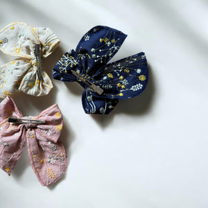 「刺繍入りのレトロシックなヘアリボン。ナチュラルカラーの生地にボタニカル柄の繊細な刺繍が施された、大きめサイズのリボンクリップ。ベビー&キッズ向けのおしゃれなヘアアクセサリー。