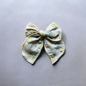 「刺繍入りのレトロシックなヘアリボン。ナチュラルカラーの生地にボタニカル柄の繊細な刺繍が施された、大きめサイズのリボンクリップ。ベビー&キッズ向けのおしゃれなヘアアクセサリー。