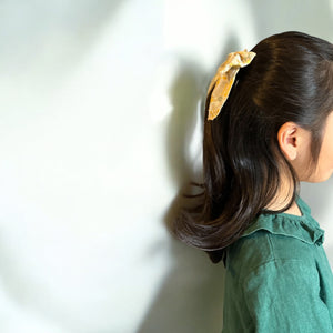 「刺繍入りのレトロシックなヘアリボン。ナチュラルカラーの生地にボタニカル柄の繊細な刺繍が施された、大きめサイズのリボンクリップ。ベビー&キッズ向けのおしゃれなヘアアクセサリー。