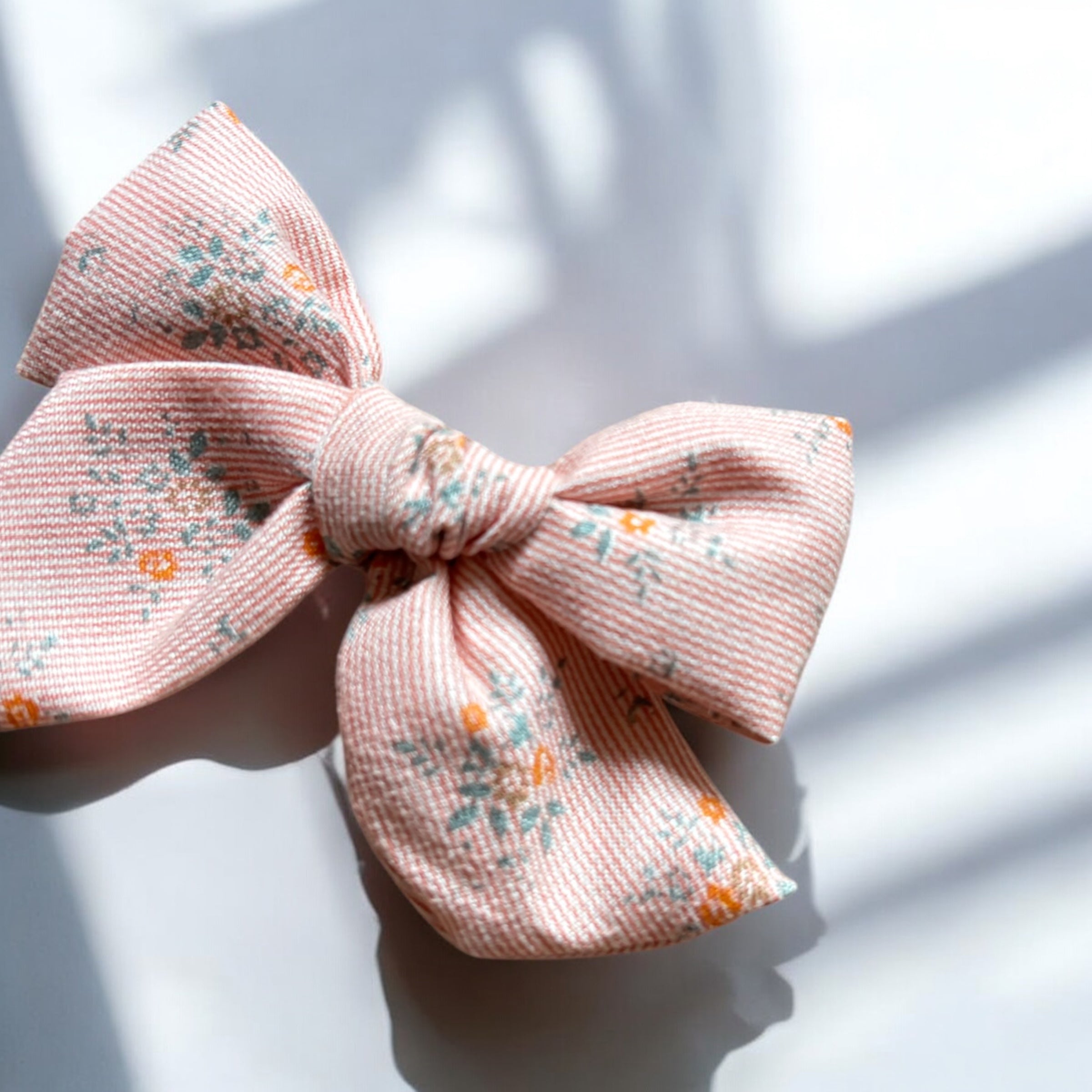 「小花柄が可愛い大きめサイズのヘアリボンクリップ。やさしいピンクカラーとナチュラルな風合いの生地が特徴で、ベビー&キッズ向けのおしゃれなヘアアクセサリー。簡単にヘアアレンジが楽しめるアイテム