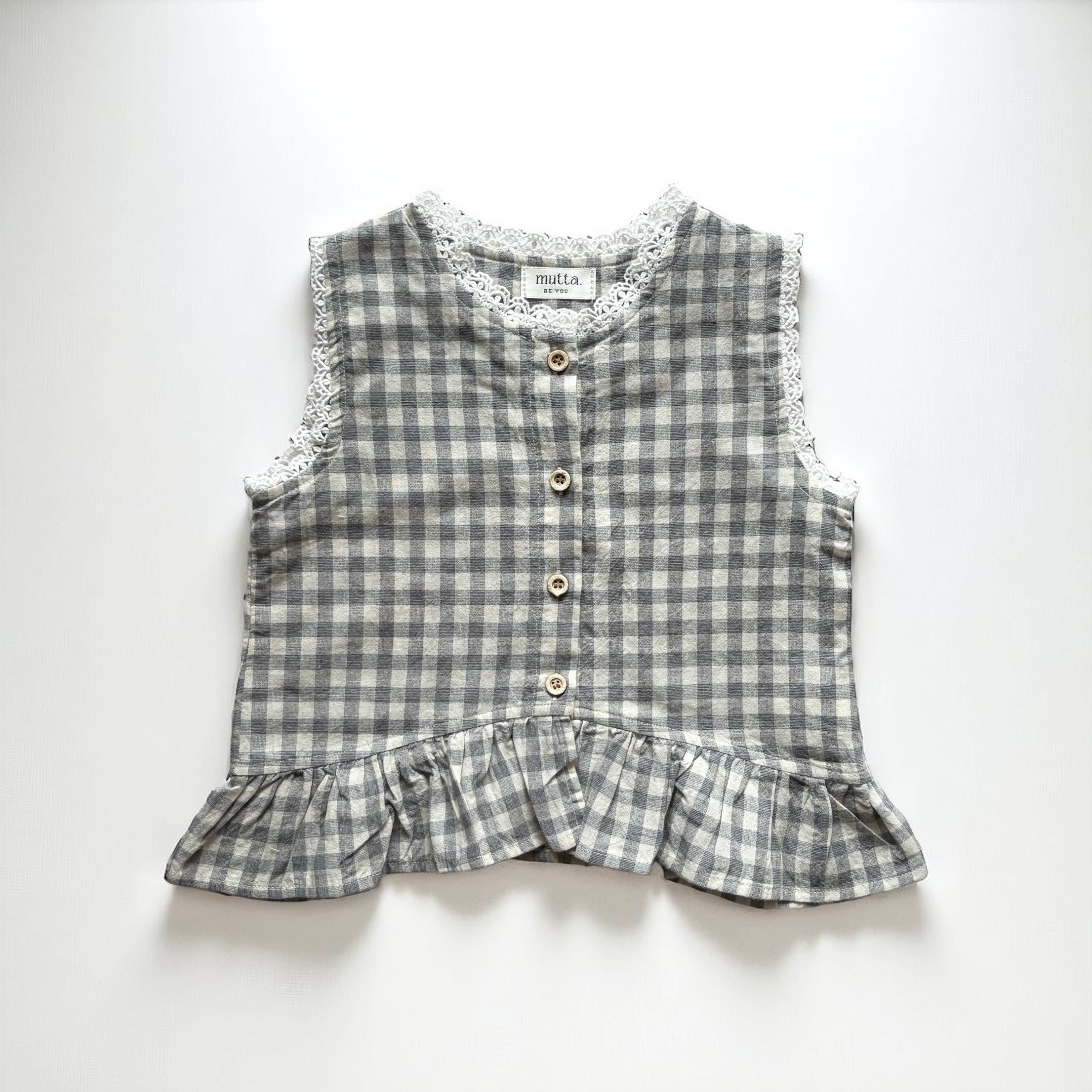 ギンガムチェック柄のノースリーブキッズトップスを着た女の子。muttaの夏の新作、涼しげなコットン素材とフリル裾が特徴