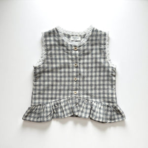 ギンガムチェック柄のノースリーブキッズトップスを着た女の子。muttaの夏の新作、涼しげなコットン素材とフリル裾が特徴