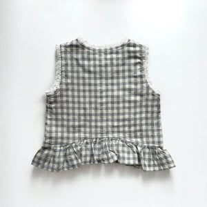 ギンガムチェック柄のノースリーブキッズトップスを着た女の子。muttaの夏の新作、涼しげなコットン素材とフリル裾が特徴