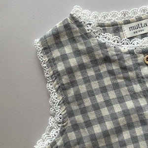 ギンガムチェック柄のノースリーブキッズトップスを着た女の子。muttaの夏の新作、涼しげなコットン素材とフリル裾が特徴