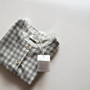 ギンガムチェック柄のノースリーブキッズトップスを着た女の子。muttaの夏の新作、涼しげなコットン素材とフリル裾が特徴