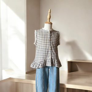 ギンガムチェック柄のノースリーブキッズトップスを着た女の子。muttaの夏の新作、涼しげなコットン素材とフリル裾が特徴