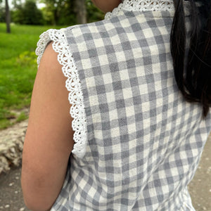 ギンガムチェック柄のノースリーブキッズトップスを着た女の子。muttaの夏の新作、涼しげなコットン素材とフリル裾が特徴